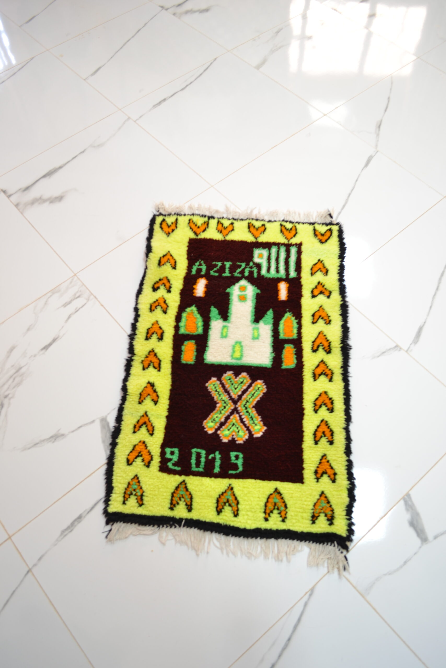 Tapis marron avec symbole et l’écriture "AZIZA"